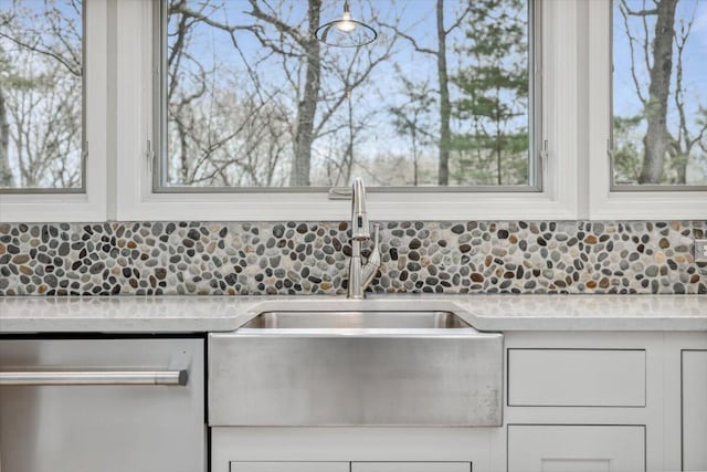 kitchen with dishwasher, a sink, white cabinets, and tasteful backsplash