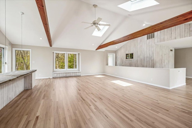 unfurnished living room with a skylight, high vaulted ceiling, baseboards, beamed ceiling, and light wood-style flooring
