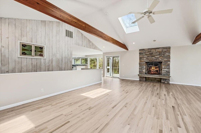 unfurnished living room featuring a skylight, high vaulted ceiling, wood finished floors, a ceiling fan, and a fireplace