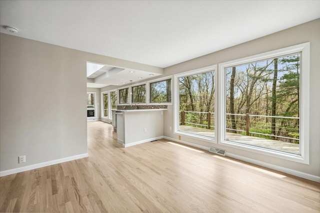 unfurnished living room with baseboards, light wood-style flooring, and plenty of natural light