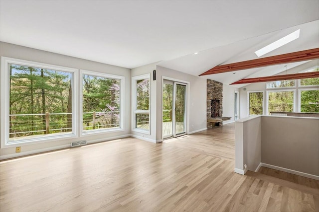 unfurnished living room with a skylight, baseboards, healthy amount of natural light, and light wood-type flooring