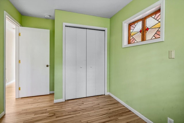 unfurnished bedroom featuring baseboards, wood finished floors, and a closet