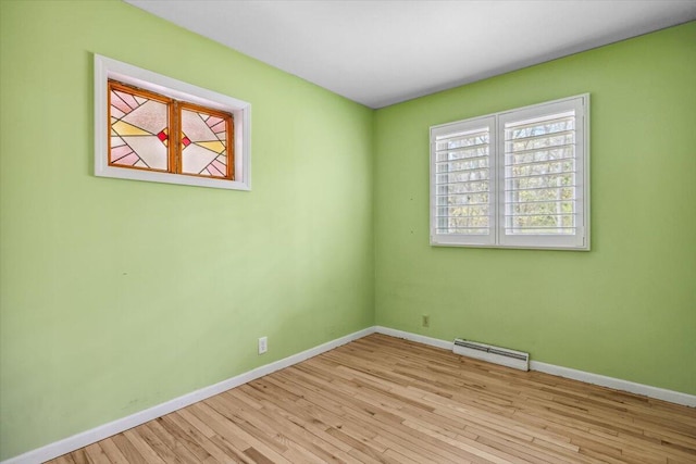 spare room featuring baseboard heating, wood finished floors, and baseboards