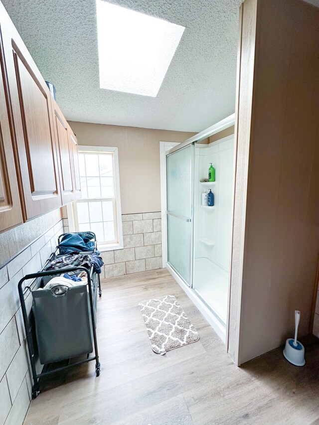 1076 N Lakeshore Rd, Harbor Beach, MI 48441 - full bath with a skylight, wood finished floors, a textured ceiling, and a shower stall