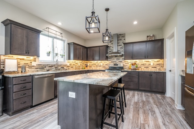 18767 Millar Rd, Clinton Township, MI 48036 - kitchen with stainless steel appliances, wall chimney exhaust hood, a sink, dark brown cabinetry, and a kitchen island