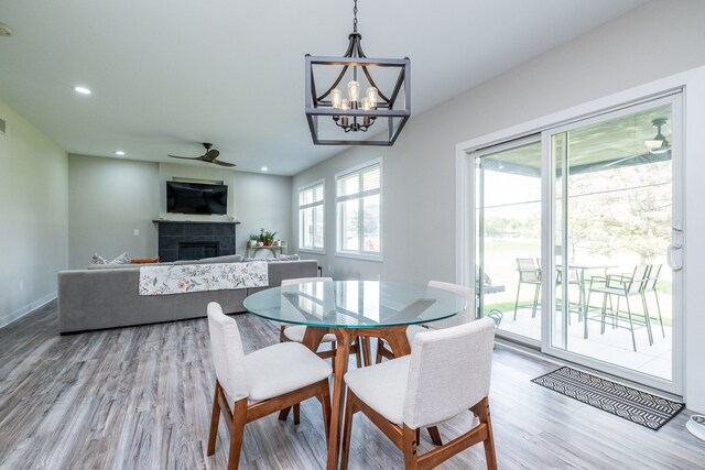 18767 Millar Rd, Clinton Township, MI 48036 - dining space featuring a tiled fireplace, light wood finished floors, a ceiling fan, a chandelier, and recessed lighting