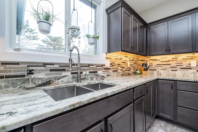 18767 Millar Rd, Clinton Township, MI 48036 - kitchen featuring a sink, backsplash, light stone countertops, dark brown cabinets, and light wood-type flooring