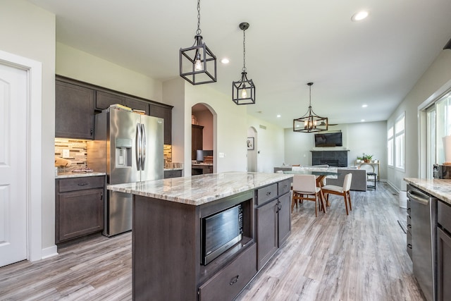 18767 Millar Rd, Clinton Township, MI 48036 - kitchen with appliances with stainless steel finishes, dark brown cabinetry, light wood-style flooring, arched walkways, and recessed lighting