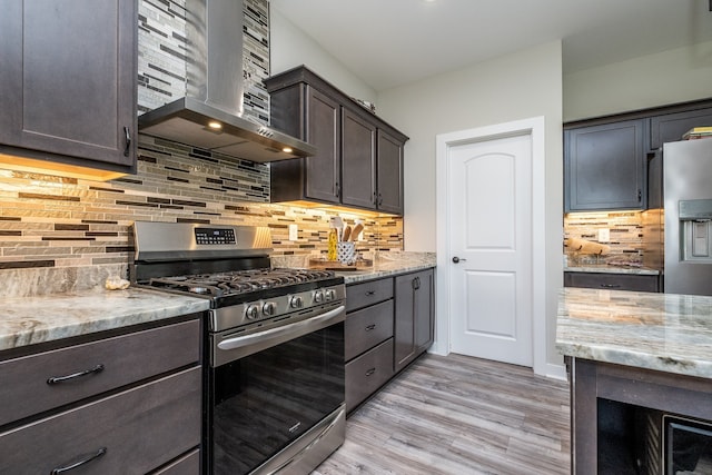 18767 Millar Rd, Clinton Township, MI 48036 - kitchen featuring stainless steel appliances, wall chimney range hood, light stone counters, light wood-style flooring, and dark brown cabinets