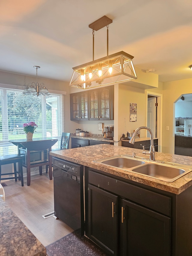 kitchen featuring black dishwasher, a sink, a chandelier, light wood-type flooring, and glass insert cabinets