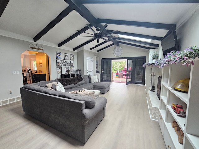 living room with light wood-type flooring, arched walkways, ceiling fan, and baseboards