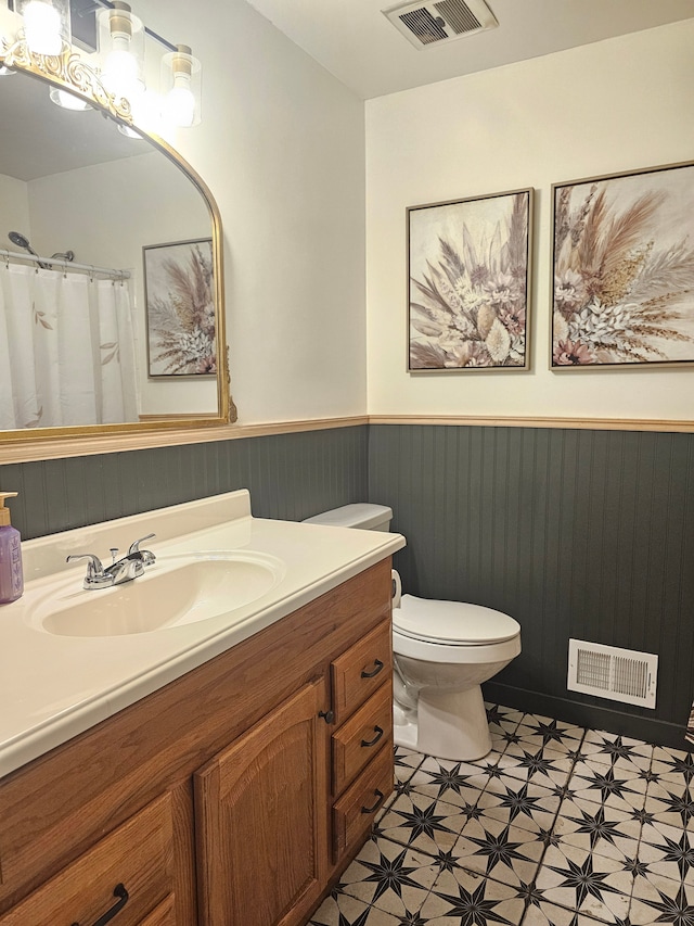 bathroom with a wainscoted wall, toilet, tile patterned floors, vanity, and a shower with shower curtain