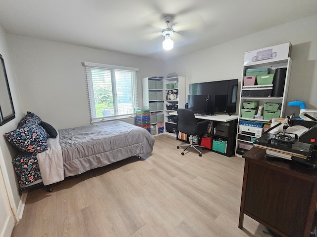 bedroom featuring light wood-style floors, an office area, and a ceiling fan