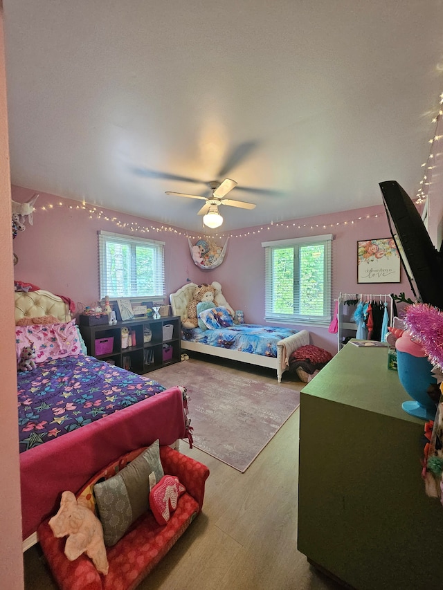 bedroom with multiple windows, wood finished floors, and ceiling fan