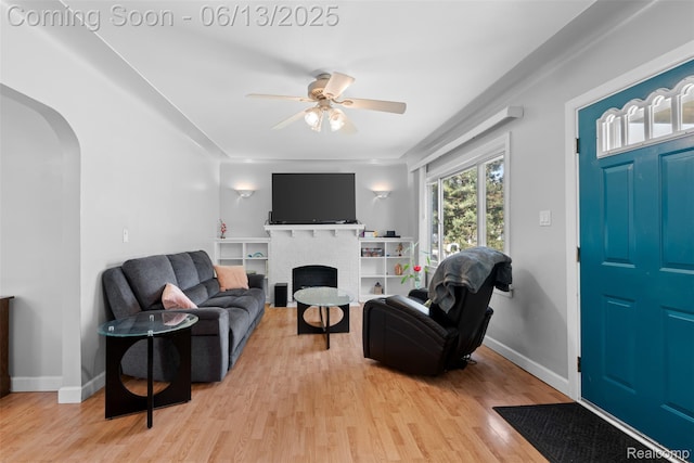 7416 Gerald Ave, Warren, MI 48092 - living room with arched walkways, light wood-style floors, a ceiling fan, and a brick fireplace