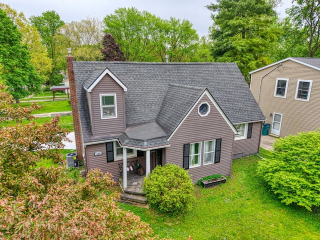 466 Wayland Ave, East Lansing, MI 48823 - view of front of home featuring central AC unit, a chimney, roof with shingles, and a front lawn