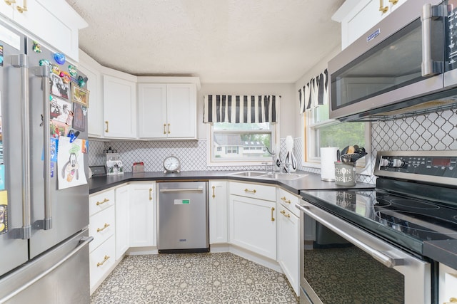 466 Wayland Ave, East Lansing, MI 48823 - kitchen featuring appliances with stainless steel finishes, backsplash, white cabinetry, and a textured ceiling