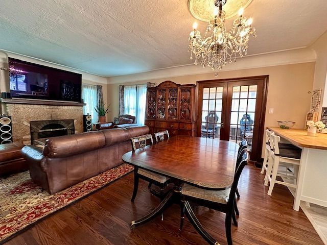 95 Mapleton Rd, Grosse Pointe Farms, MI 48236 - dining space featuring a chandelier, french doors, wood finished floors, a textured ceiling, and a fireplace