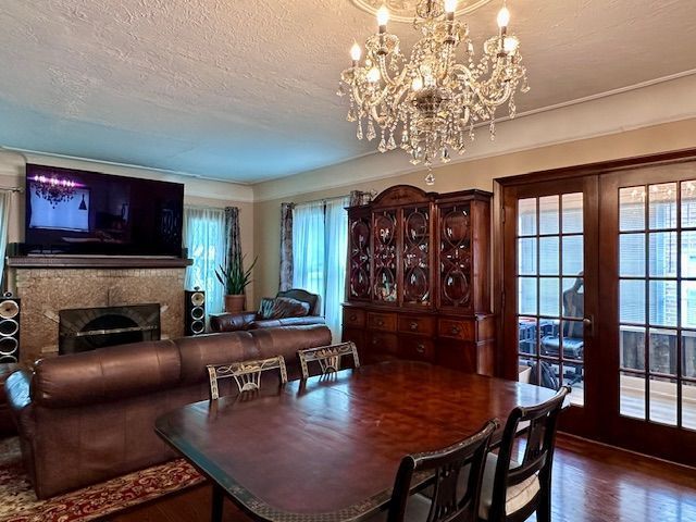 95 Mapleton Rd, Grosse Pointe Farms, MI 48236 - dining room with a chandelier, wood finished floors, a textured ceiling, and a fireplace
