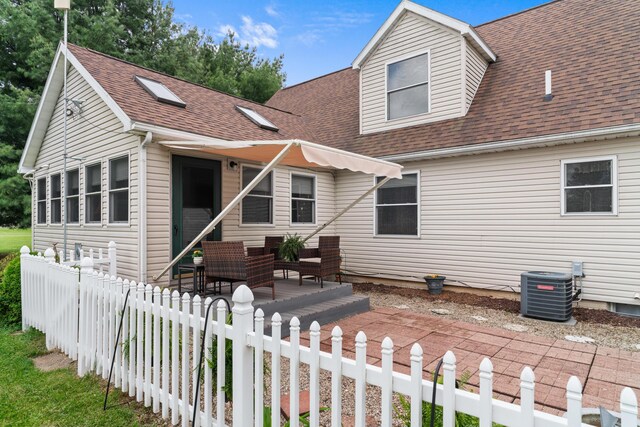 336 Jonesville Rd, Jonesville, MI 49250 - view of front of house featuring roof with shingles, central AC, a fenced front yard, and a patio