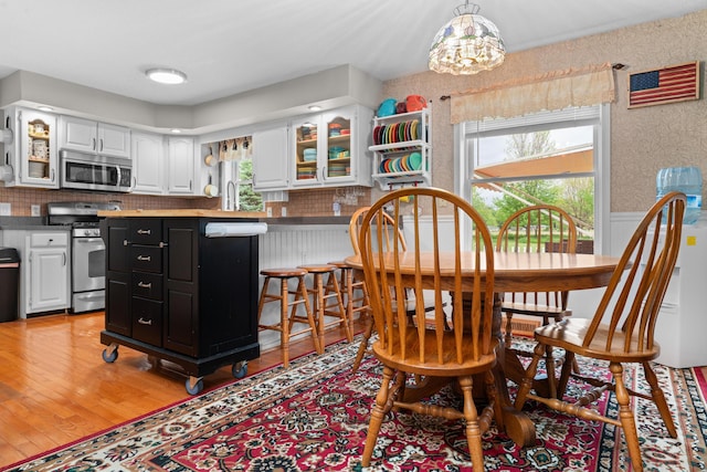 336 Jonesville Rd, Jonesville, MI 49250 - dining area with a chandelier, plenty of natural light, light wood finished floors, and wainscoting