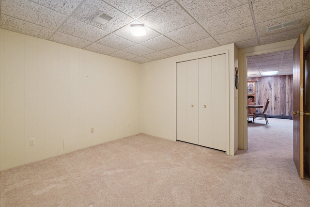 11928 Shenandoah Unit 3, South Lyon, MI 48178 - unfurnished bedroom with carpet floors, wooden walls, a drop ceiling, and a closet