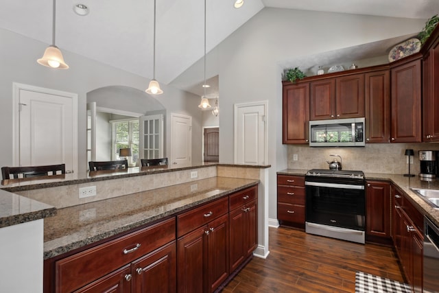 416 Enclave Ct SE Unit 2, Grand Rapids, MI 49546 - kitchen with stainless steel appliances, dark stone countertops, arched walkways, hanging light fixtures, and tasteful backsplash