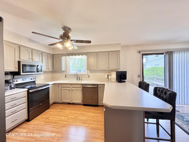 2880 Wurtzel Dr, Freeland, MI 48623 - kitchen featuring stainless steel appliances, a peninsula, a breakfast bar area, a sink, and light wood-style flooring