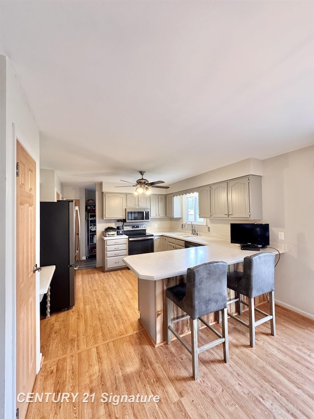 2880 Wurtzel Dr, Freeland, MI 48623 - kitchen featuring appliances with stainless steel finishes, a peninsula, light wood finished floors, a breakfast bar, and light countertops