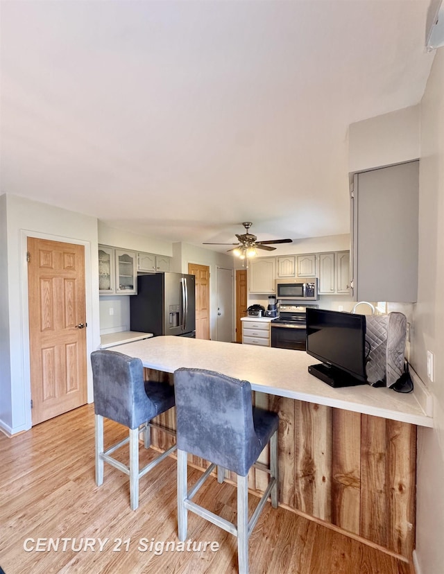 2880 Wurtzel Dr, Freeland, MI 48623 - kitchen featuring stainless steel appliances, a peninsula, light wood finished floors, light countertops, and a breakfast bar