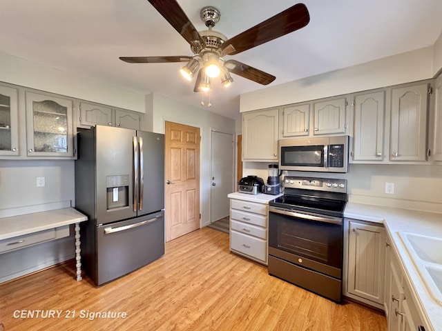 2880 Wurtzel Dr, Freeland, MI 48623 - kitchen with appliances with stainless steel finishes, gray cabinetry, a ceiling fan, light countertops, and glass insert cabinets