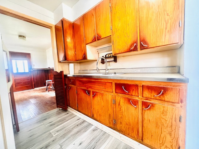 20760 Atlantic Ave, Warren, MI 48091 - kitchen featuring a sink, light wood-style floors, wainscoting, light countertops, and brown cabinets