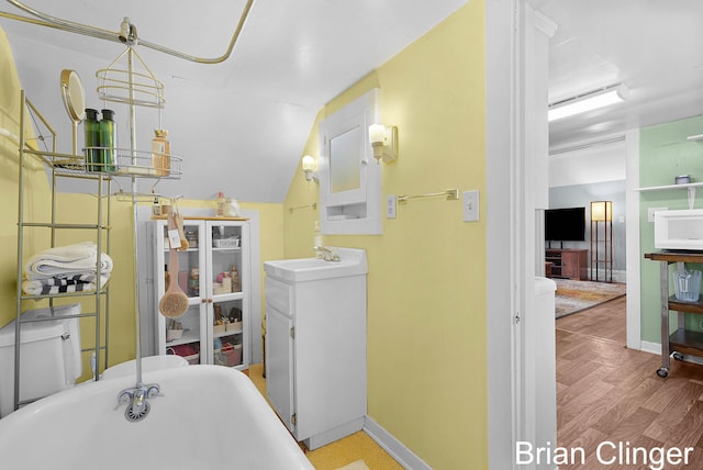 117 Palmer St NE, Grand Rapids, MI 49505 - bathroom featuring a freestanding tub, baseboards, vanity, wood finished floors, and lofted ceiling