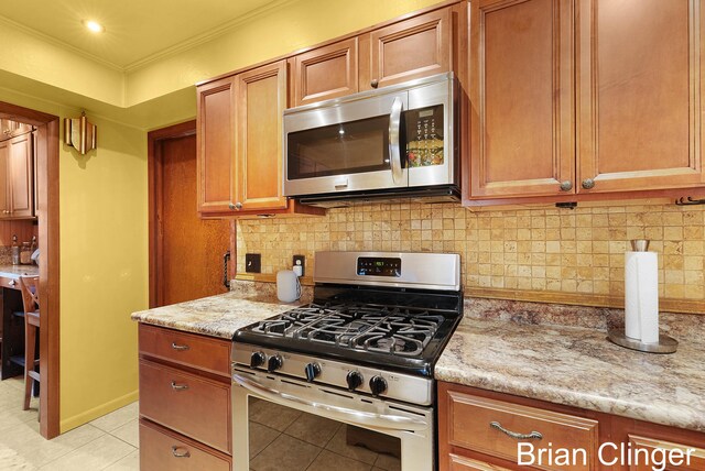 117 Palmer St NE, Grand Rapids, MI 49505 - kitchen with appliances with stainless steel finishes, light tile patterned flooring, tasteful backsplash, light stone countertops, and ornamental molding