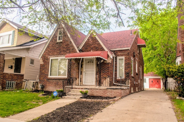 5790 Lakepointe St, Detroit, MI 48224 - tudor house with brick siding, an outdoor structure, a shingled roof, driveway, and a front yard