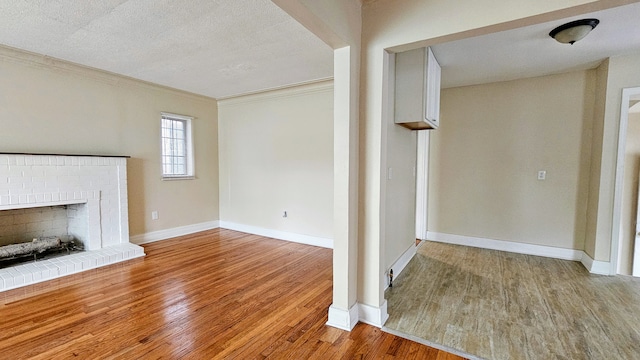 5790 Lakepointe St, Detroit, MI 48224 - unfurnished living room with light wood-style floors, baseboards, ornamental molding, a brick fireplace, and a textured ceiling