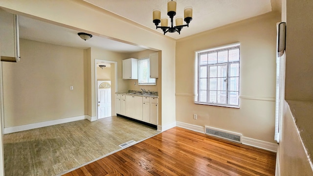 5790 Lakepointe St, Detroit, MI 48224 - kitchen with light wood-style floors, white cabinets, baseboards, a chandelier, and light countertops