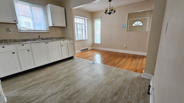 5790 Lakepointe St, Detroit, MI 48224 - kitchen featuring light wood finished floors, baseboards, white cabinets, a chandelier, and light stone countertops