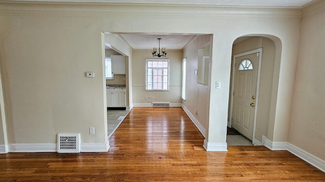 5790 Lakepointe St, Detroit, MI 48224 - foyer entrance featuring light wood finished floors, ornamental molding, arched walkways, a chandelier, and baseboards
