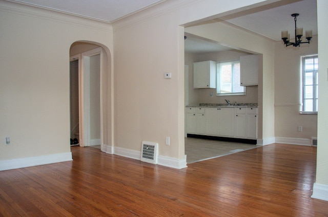 5790 Lakepointe St, Detroit, MI 48224 - unfurnished living room with arched walkways, a chandelier, wood finished floors, crown molding, and a sink