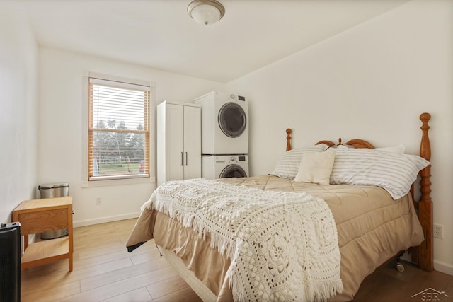 6115 N Belsay Rd, Flint, MI 48506 - bedroom with stacked washer / drying machine, light wood-style floors, and baseboards