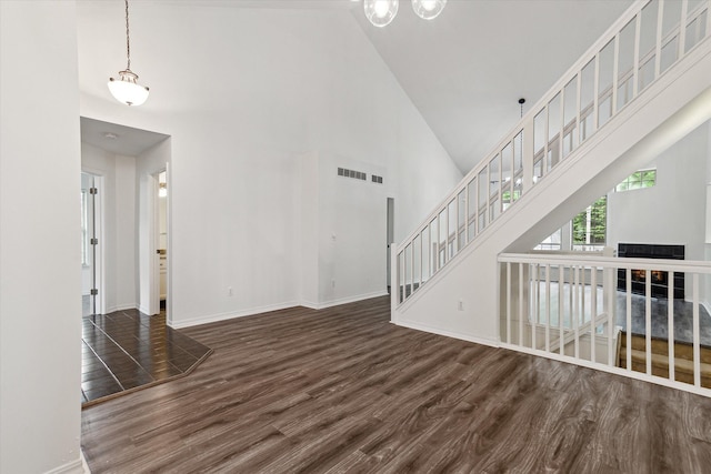 5496 Michael Dr, Ypsilanti, MI 48197 - unfurnished living room with high vaulted ceiling, wood finished floors, stairway, and baseboards