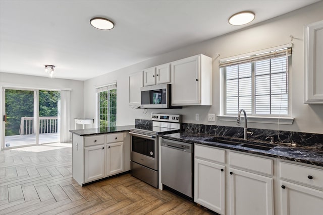 5496 Michael Dr, Ypsilanti, MI 48197 - kitchen featuring stainless steel appliances, a sink, a peninsula, white cabinetry, and dark stone counters
