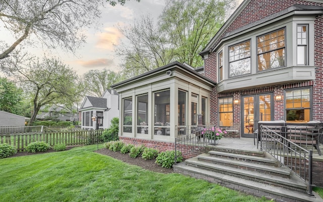 316 Chesterfield Ave, Birmingham, MI 48009 - back of house at dusk with a sunroom, brick siding, and a patio