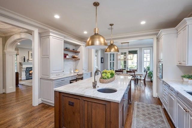 316 Chesterfield Ave, Birmingham, MI 48009 - kitchen with a sink, open shelves, white cabinets, dark wood-style floors, and an island with sink