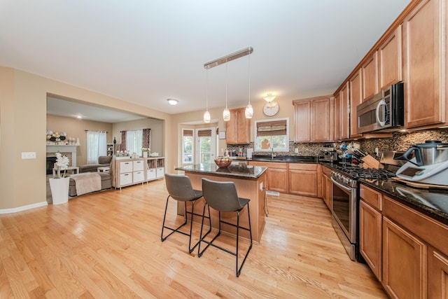 57677 Blossom Valley Trl, New Hudson, MI 48165 - kitchen with stainless steel appliances, a breakfast bar area, backsplash, and light wood-style flooring