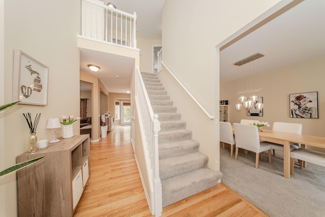 57677 Blossom Valley Trl, New Hudson, MI 48165 - stairs featuring wood finished floors and a chandelier