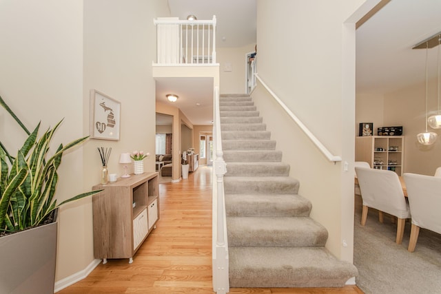 57677 Blossom Valley Trl, New Hudson, MI 48165 - staircase with wood finished floors, a high ceiling, and baseboards