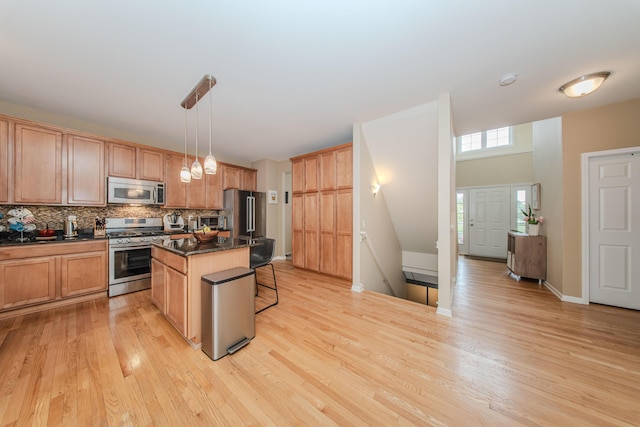57677 Blossom Valley Trl, New Hudson, MI 48165 - kitchen featuring appliances with stainless steel finishes, dark countertops, a breakfast bar, light wood finished floors, and decorative backsplash