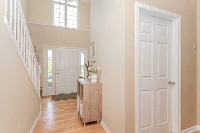 57677 Blossom Valley Trl, New Hudson, MI 48165 - entrance foyer featuring light wood-style flooring, stairs, baseboards, and a high ceiling